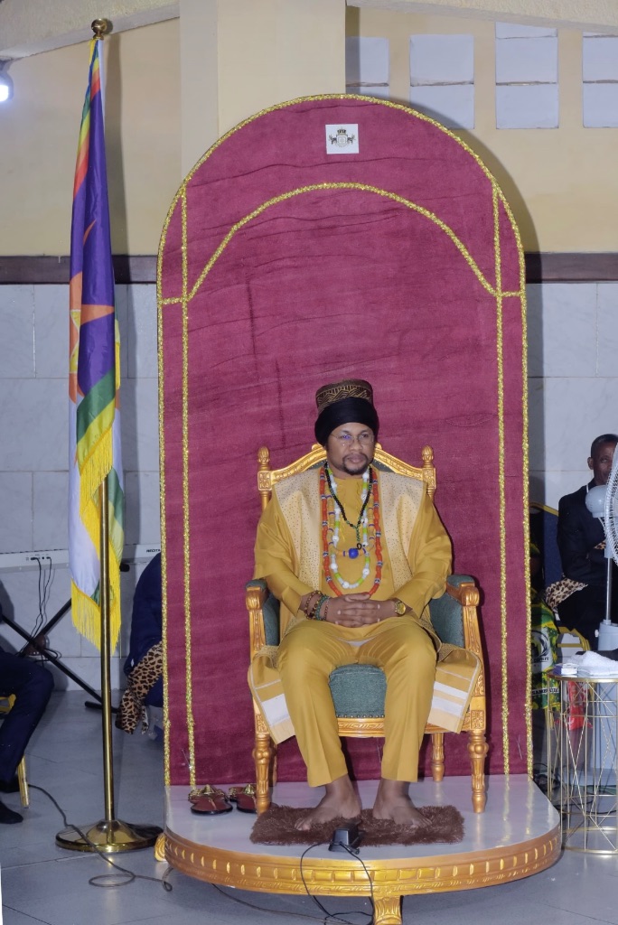 Sa Majesté Masambukidi Ier sur le trône royal, sous les armoiries