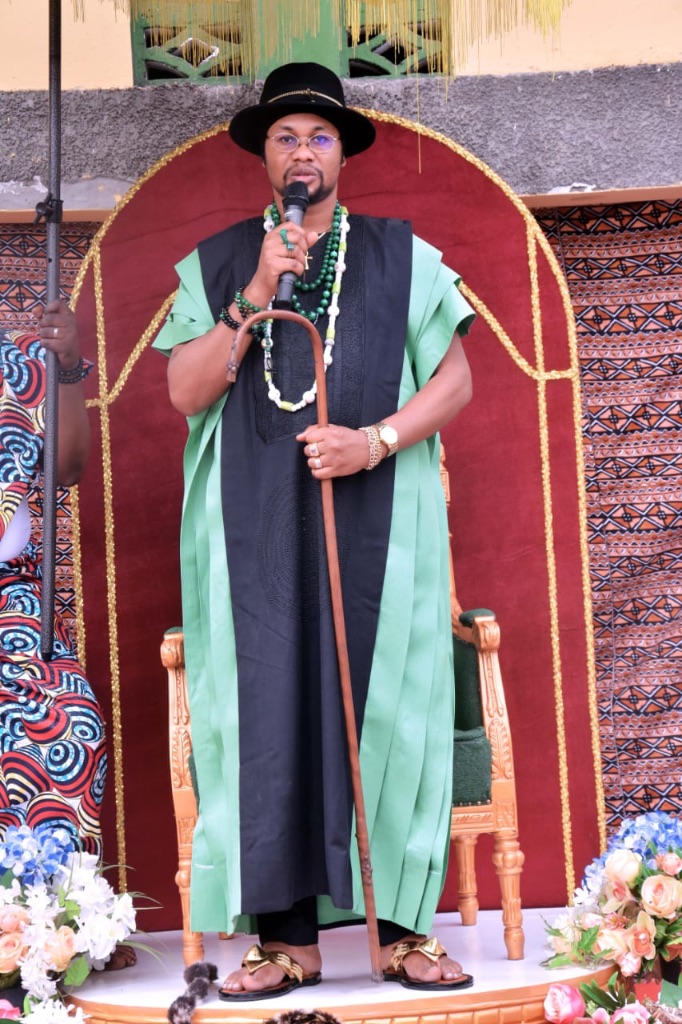 Sa Majesté Masambukidi Ier tenant le microphone, debout devant l'arche royale — cérémonie officielle